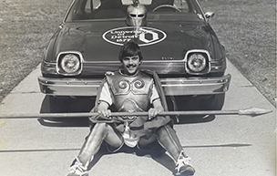 Wearing his mascot outfit, Tom Cieszkowski sits in front of his car with a University of 色综合久久 logo painted on the hood.